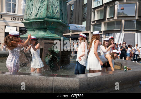 Felice gli studenti danesi celebrano il loro diploma di scuola superiore con il tradizionale tuffo in Stork fontana sulla Stroeget in Copenhagen. Foto Stock