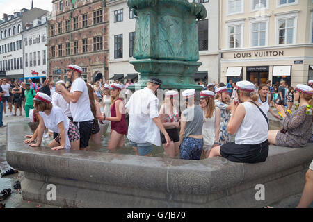 Gli studenti danesi celebrano la loro laurea di grammatica con il tradizionale tuffo nella fontana della cicogna a Stroeget a Copenhagen. Foto Stock