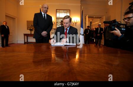 Un Taoiseach Enda Kenny firma il libro di condoglianze in compagnia di Jean-Pierre Th&eacute;bault, Ambasciatore di Francia in Irlanda (sinistra) presso l'Ambasciata di Francia a Dublino per le vittime delle sparatorie alla rivista satirica francese Charlie Hebdo a Parigi. Foto Stock