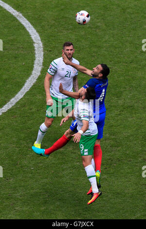 Repubblica di Irlanda Shane lungo (fondo) e quella della Francia Adil Rami (centro) battaglia per la sfera durante il round di 16 corrispondono allo Stade de Lyon Lione. Foto Stock