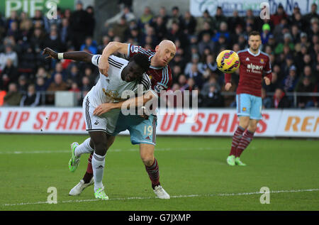 Il Bafetimbi Gomis di Swansea City (a sinistra) non riesce a segnare con la testa come James Collins di West Ham United, afferra con le spalle dell'uomo di Swansea, durante la partita della Barclays Premier League al Liberty Stadium di Swansea. Foto Stock