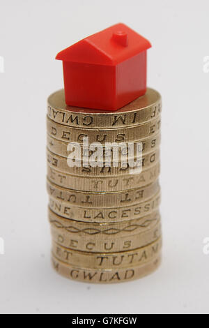 Un modello di plastica di una casa si siede su un palo di una libbra monete Foto Stock