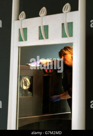 Sarah Gerrish, Furniture and Wooden Artifact Conservator, strofina la "Libreria per Windyhill" riflessa nel "Mirror for Windyhill", mentre la Glasgow School of Art mette in mostra i mobili di Mackintosh salvati dal fuoco in una nuova galleria di mobili nel Reid Building, Che farà parte del tour delle Scuole d'Arte di Mackintosh da domenica 1 febbraio 2015. Foto Stock