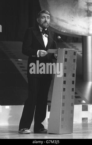 Un bow-tie e scarpe da baseball per il milionario poeta pop Rod McKuen mentre legge le nomination per l'Anthony Asquith Memorial Award durante la presentazione della British Academy of Film and Television Arts 1975 Awards alla Royal Albert Hall, Londra. Rod ha accettato il premio per conto di John Williams per il suo punteggio originale per il film 'Jaws'. Foto Stock