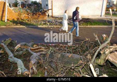 La gente del posto fa un'indagine su un muro danneggiato e alberi caduti dal mini-tornado di ieri. Foto Stock