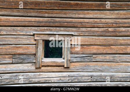 Una piccola finestra sporca su un rustico di parete di registro Foto Stock