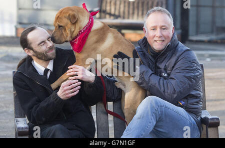 Kai il cane con il suo nuovo proprietario Ian Russell (a destra) e l'assistente per la cura degli animali senior Alan Grant (a sinistra) presso un ufficio scozzese SPCA a Glasgow, dopo essere stato abbandonato in una stazione ferroviaria con una valigia piena dei suoi beni. Foto Stock