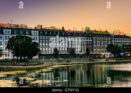 Edifici con neon di insegne pubblicitarie sui tetti accanto al Sortedams Sø, Copenhagen, durante il tramonto. Foto Stock