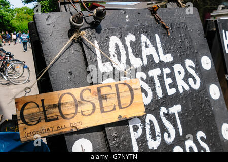 Cartello in un negozio locale di pubblicità posters e memorabelia, con un altro segno dicendo che è chiuso tutto il giorno il lunedì. Foto Stock