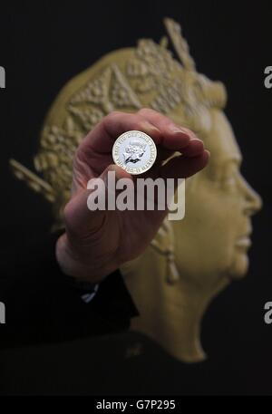 Un assistente di eventi della zecca reale tiene una nuova moneta da due libbre davanti al ritratto di Jody Clark del nuovo inconio della regina Elisabetta II durante una cerimonia di inaugurazione per l'ultimo ritratto di conio della regina Elisabetta II alla National Portrait Gallery di Londra. Foto Stock