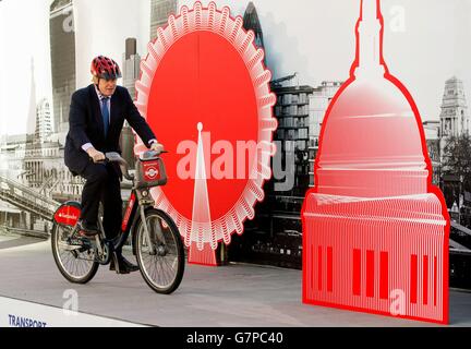 Il Sindaco di Londra Boris Johnson corre una bicicletta a noleggio in occasione di un evento di lancio nel centro di Londra che annuncia Santander come il nuovo sponsor del programma di noleggio biciclette di Londra. Foto Stock