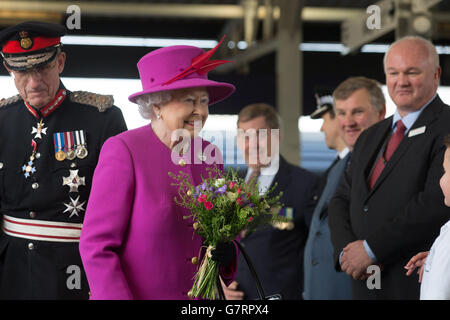 La regina Elisabetta II sorride dopo essere stata presentata con i fiori dai bambini delle scuole locali quando arriva alla stazione ferroviaria di Plymouth, prima di una visita HMS Ocean, alla base navale HM Devonport, a Plymouth, Devon. Foto Stock
