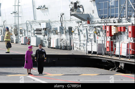 Regina Elisabetta II accompagnata dal Capitano Timothy Henry (a destra), Comandante dell'Oceano HMS prima di partire in elicottero dopo aver visitato la nave d'assalto anfibia, ormeggiata alla base navale HM Devonport, a Plymouth, Devon. Foto Stock