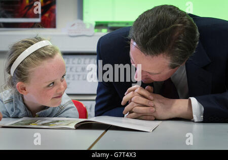 Il primo Ministro David Cameron aiuta con una lezione di lettura alla Scuola primaria Cattolica Romana del Sacro cuore a Westhoughton, vicino a Bolton, con Lucy Howarth, di sei anni, mentre si trova sulla pista della campagna elettorale Generale. Foto Stock