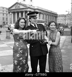 Sue Wang, 18 anni, da Singapore (a sinistra) e Barbara Yung, 20 anni, da Hong Kong, parlano con un poliziotto in Trafalgar Square il capodanno cinese. Sono tra i 15 finalisti che gareggeranno per il titolo Miss Chinatown 1980, organizzato dalla Camera di Commercio Cinese. Foto Stock