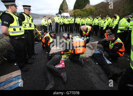 I dimostranti anti anti anti anti-tridente che si sono collegati con le tubature li hanno tagliati dalla polizia all'ingresso sud della base navale di HM Clyde, Faslane. Foto Stock