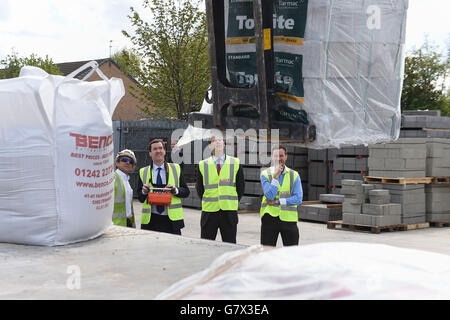 Il cancelliere George Osborne prende i comandi di una gru HGV sotto la supervisione del conducente Alan Phillips (sinistra) come candidato parlamentare del Partito conservatore Alex Chalk (secondo da destra) e amministratore delegato Paul Bence (destra) guardare durante una visita a George Bence & Sons commerciante costruttori a Cheltenham. Foto Stock