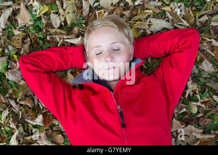 Giovane donna sdraiata su foglie di autunno Foto Stock