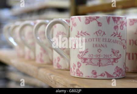 Le tazze commemorative decorate a mano che celebrano la nascita della principessa Charlotte sono esposte al Burleigh Pottery di Stoke-on-Trent, Staffordshire. Foto Stock