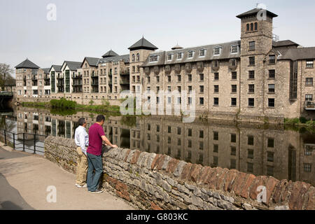 Regno Unito, Cumbria, Kendal uomini rilassante accanto al fiume Kent opposta a Riverside Hotel Foto Stock