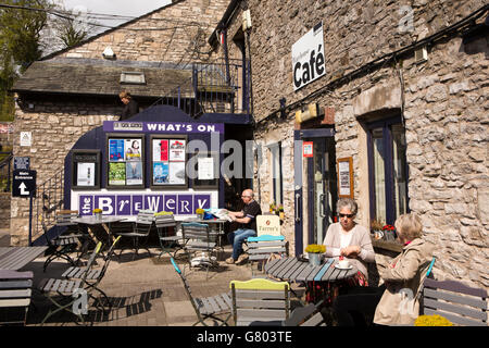 Regno Unito, Cumbria, Kendal Highgate, Brewery Arts Centre di clienti presso il Magazzino café seduta nella luce del sole Foto Stock