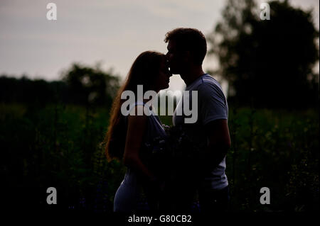 Amare giovane uomo e donna silhouette nera contro il luminoso tramonto data la natura Foto Stock