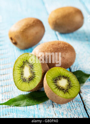 Kiwi freschi palo con foglie posti su vecchie tavole di legno Foto Stock