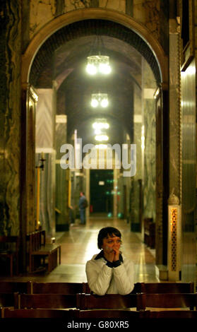 Una signora si siede all'interno della Cattedrale di Westminister, Londra, come il suo annuito dal Vaticano che il Papa ha finalmente soccombuto alla sua malattia persistente e morì alle 20.37. Foto Stock