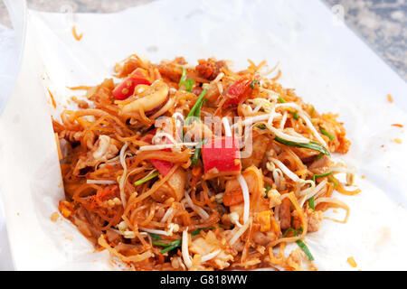 Spaghettini fritti in stile Thai con gamberi. Friggere gli spaghetti con frutti di mare (Pad Thai) cucina tailandese sul colore bianco involucro alimentare. Foto Stock