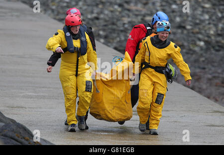 British Divers Marine Life Rescue trasporta le attrezzature che arrivano per tendere a frangenti balene pilota sulle rocce di Staffin Island sull'isola di Skye. Foto Stock