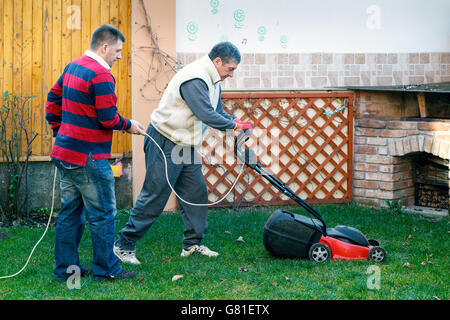 Giovane uomo aiutando senior l uomo è il giardinaggio, attività di uso domestico Foto Stock