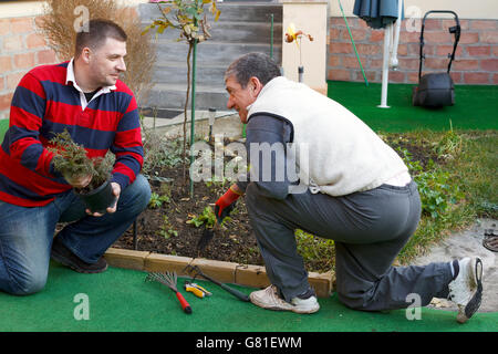 Giovane uomo aiutando senior l uomo è il giardinaggio, attività di uso domestico Foto Stock