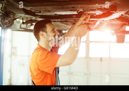 Meccanico di automobili che fissa un auto in garage in concessionaria Foto Stock