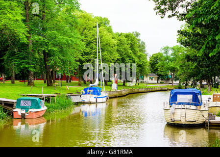 Soderkoping, Svezia - 20 Giugno 2016: barche ormeggiate nel fiume Storan con parco pubblico accanto al molo. Foto Stock