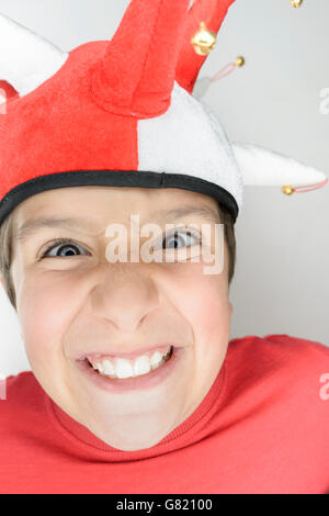 8 anni bambino in un costume giullari tirando funny faces Foto Stock