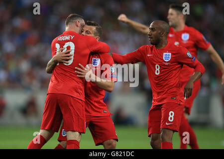 Il Jack Jack Wilshere (centro) dell'Inghilterra festeggia con il compagno di squadra Wayne Rooney (a sinistra e Fabian Delph (a destra) dopo aver segnato i suoi lati il primo obiettivo della partita durante la partita di qualificazione del Campionato europeo UEFA allo Stozice Stadium, Slovenia. Foto Stock