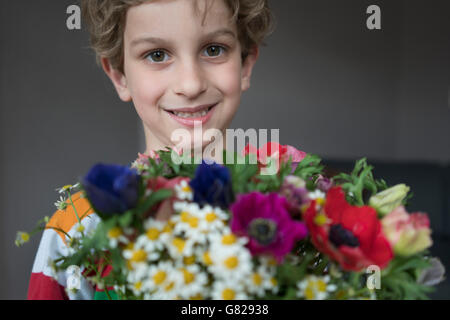 Close-up verticale di sorridere boy holding mazzo di fiori Foto Stock