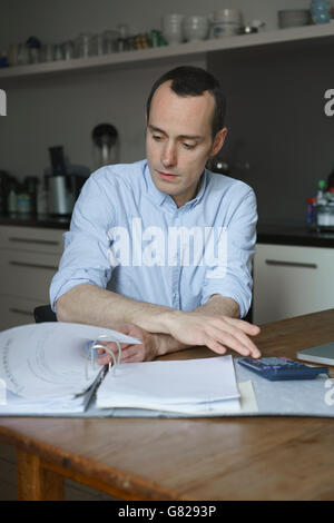Uomo serio facendo documentazione sul tavolo a casa Foto Stock