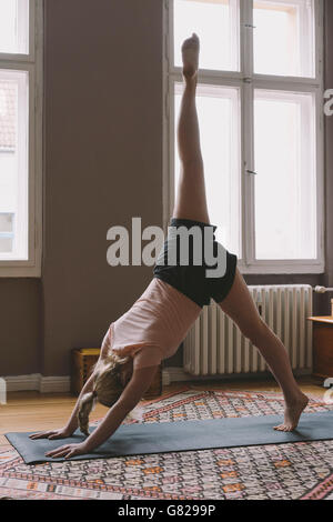 Giovane donna a praticare yoga in salotto Foto Stock