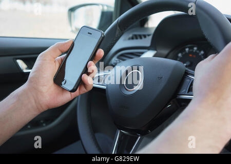 Immagine ritagliata della mano che tiene il telefono cellulare mentre si guida auto Foto Stock
