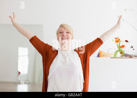 Sorridente metà donna adulta con le braccia aperte a casa Foto Stock