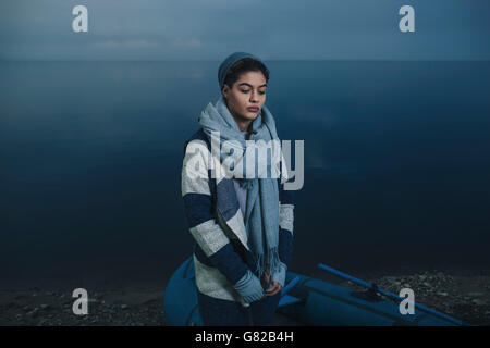 Ragazza adolescente in abiti caldi in piedi da zattera gonfiabile sul lungolago Foto Stock