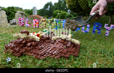 Hannah Reed, costruttore di modelli, colloca un po' di fango proveniente da un'azienda agricola dietro le figure LEGO dei cursori di fango di Glastonbury nella nuovissima scena Miniland del Glastonbury Festival a Legoland, Windsor. Foto Stock