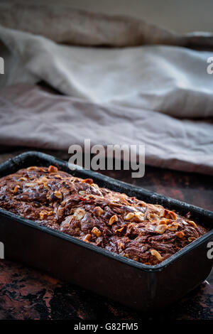 Pane alla banana con nutella swirl e nocciole tritate nella teglia. Cibo scure della fotografia. Testo libero spazio. Foto Stock