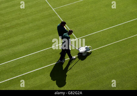 Le linee sono dipinte sul campo piacevole prima del giorno tre dei Campionati di Wimbledon all'All England Lawn Tennis and Croquet Club, Wimbledon. Foto Stock