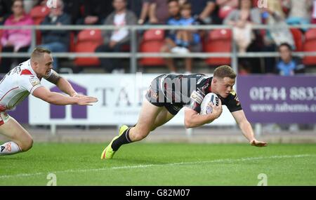 Wigan Warriors Joe Burgess va oltre per provare St Helens Adam Swift (a sinistra), durante la prima partita di Utility Super League a Langtree Park, St Helens. Foto Stock