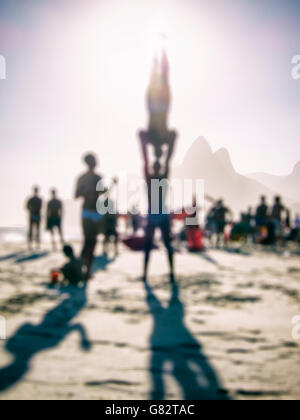 Silhouette di defocus rendendo funambolico pone di fronte un luminoso Sunset beach scena presso la spiaggia di Ipanema di Rio de Janeiro in Brasile Foto Stock