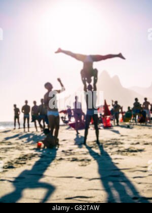 Silhouette di defocus rendendo funambolico pone di fronte un luminoso Sunset beach scena presso la spiaggia di Ipanema di Rio de Janeiro in Brasile Foto Stock