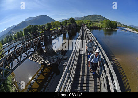 Gli escursionisti attraversano un ponte pedonale sul fiume Lochy vicino a Fort William, poiché le temperature potrebbero colpire oggi il più caldo dell'anno - ma si prevede che anche le tempeste torrenziali e le tempeste "intense" spazzino in tutto il paese. Foto Stock