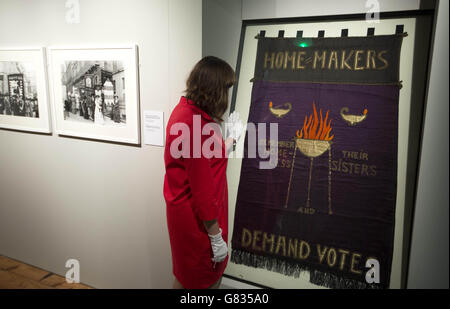 SOLO PER USO EDITORIALE la curatrice della mostra Anna Sparham, ispeziona una bandiera a suffragette presso il Museum of London Docklands prima dell'apertura della loro ultima mostra Soldaters and Suffragettes: The Photography of Christina Broroom, una mostra gratuita che apre al pubblico da venerdì 19 giugno. Foto Stock